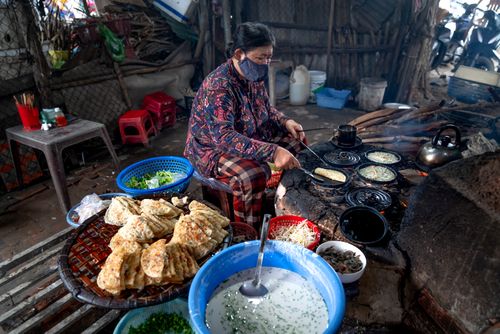 Free Asian woman cooking street food with face mask, showcasing traditional Asian culinary practices. Stock Photo