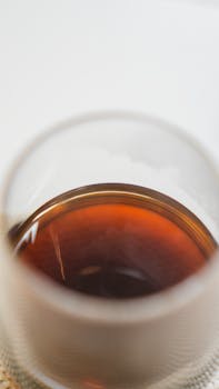 A detailed view of brewed coffee in a glass cup highlighting textures and rich color.