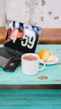 Cup of coffee with laptop and bread on rustic table. Perfect morning workspace.