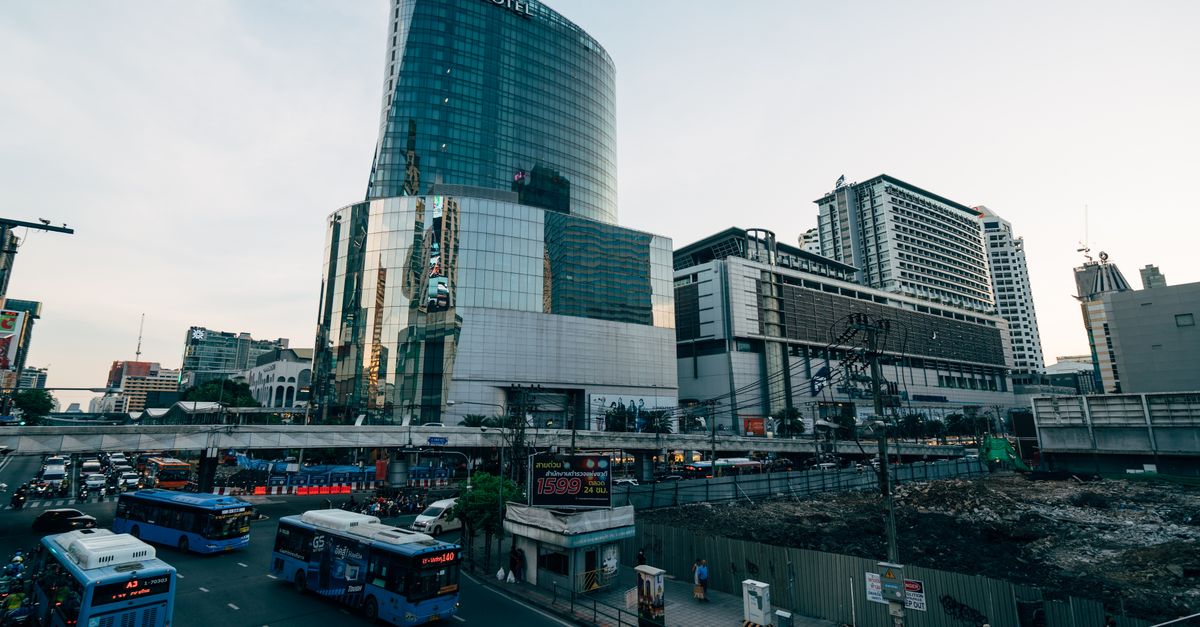 Explore the bustling urban landscape of downtown Bangkok featuring high-rise architecture and busy streets.