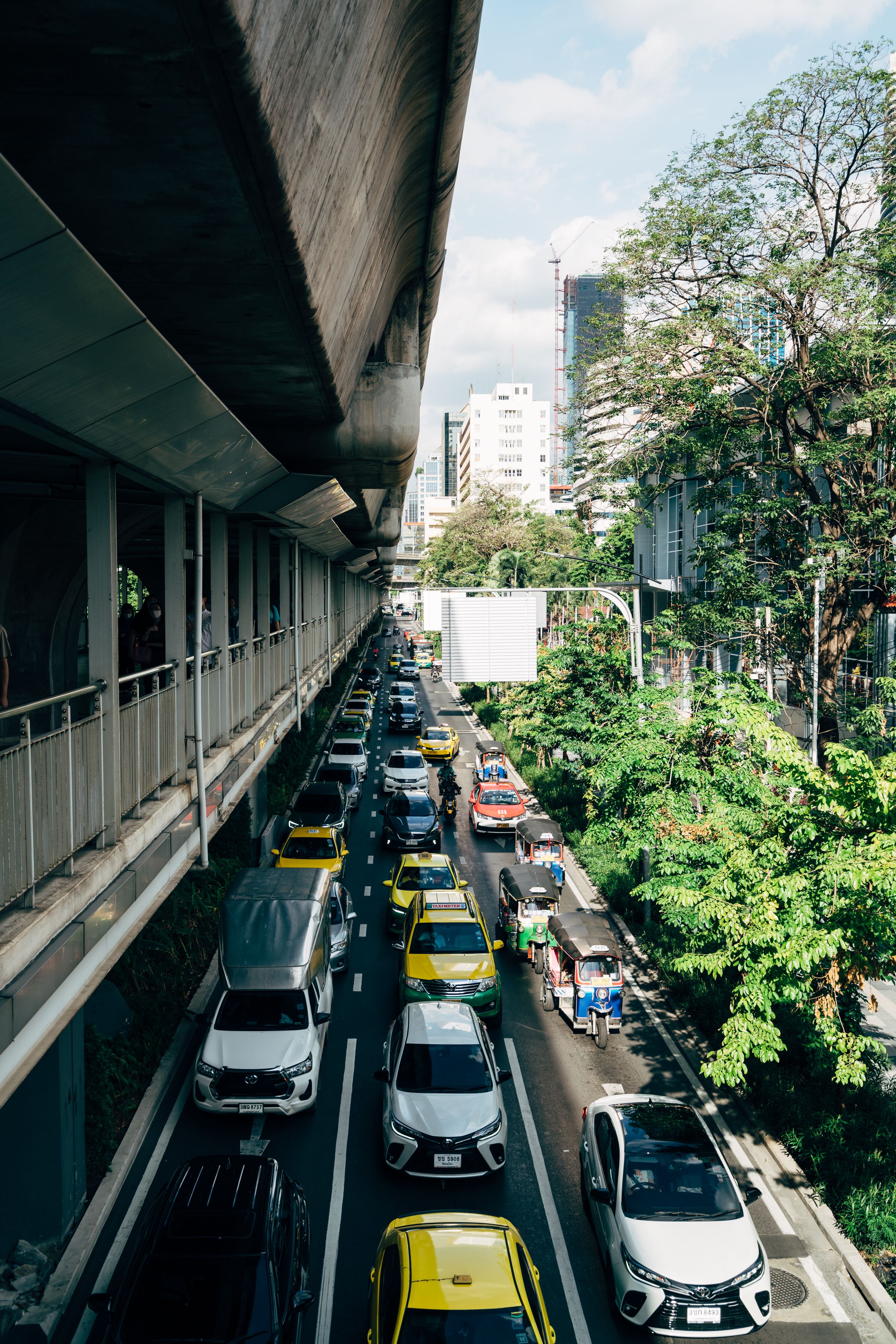 A bustling city street with busy traffic under an elevated road.
