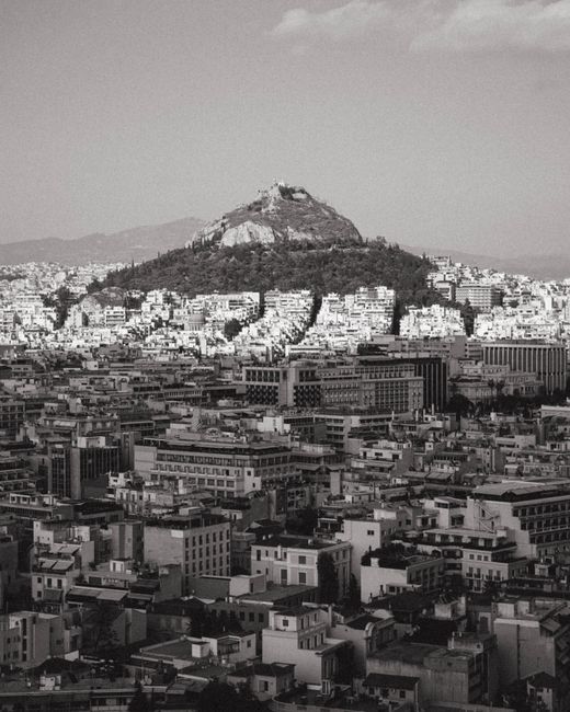 A panoramic view of Athens with Lycabettus Hill in black and white, showcasing urban landscape.