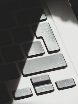 Dramatic light and shadow on a laptop keyboard, emphasizing texture and contrast.
