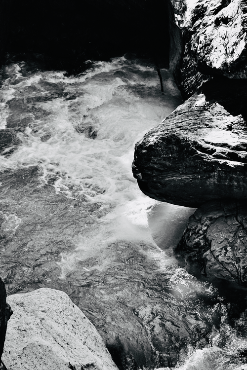 Free Black and white close-up of water flowing over rocks, creating a small waterfall. Stock Photo