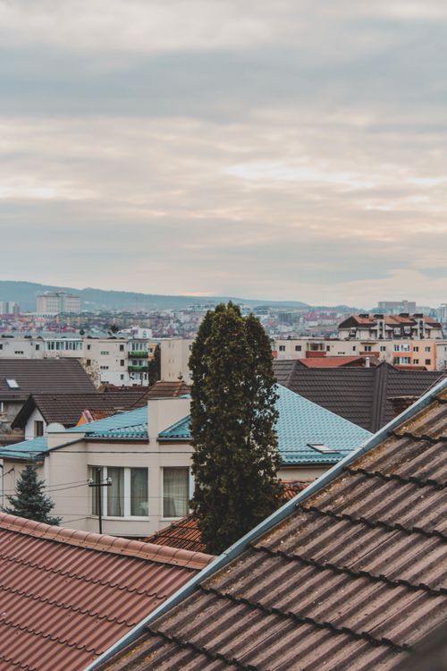 Free A picturesque view of urban rooftops under a cloudy sky, showcasing diverse architecture. Stock Photo