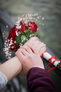 Close-up of a couple's hands holding a bouquet and each other, symbolizing love and commitment.