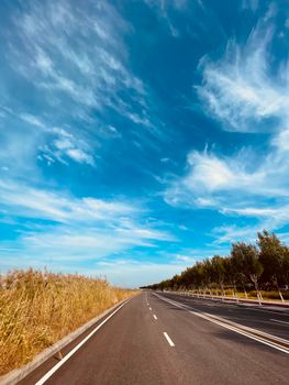 Stunning open road in Lvjuhe Town, Tianjin with clear blue skies and white clouds.