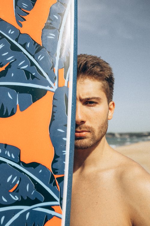 Free Shirtless man with surfboard on sunny beach day, half-face view. Stock Photo