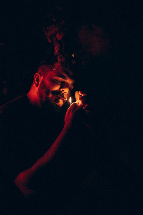 Free Dramatic low-light portrait of a man using a lighter to ignite a cigarette. Stock Photo