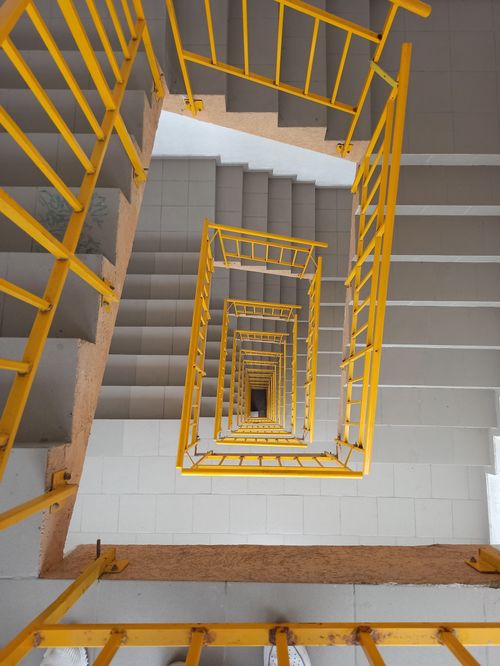 Free A vertical shot of a spiral staircase with striking yellow railings. Stock Photo
