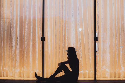 Silhouette of a Woman in a Cowboy Hat Sitting on the Floor 