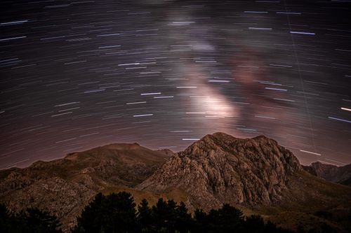 Free Long exposure of star trails creating a stunning night sky over rugged mountain terrain. Stock Photo