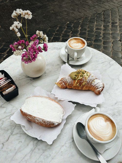 Free A charming café table with croissants, cappuccino, and flowers. Perfect breakfast scene. Stock Photo