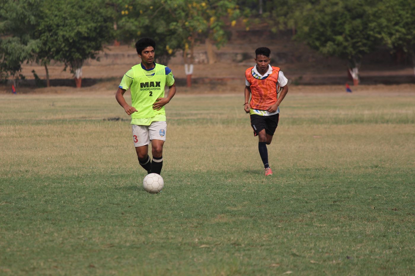 Players training on an outdoor grassroots pitch in India