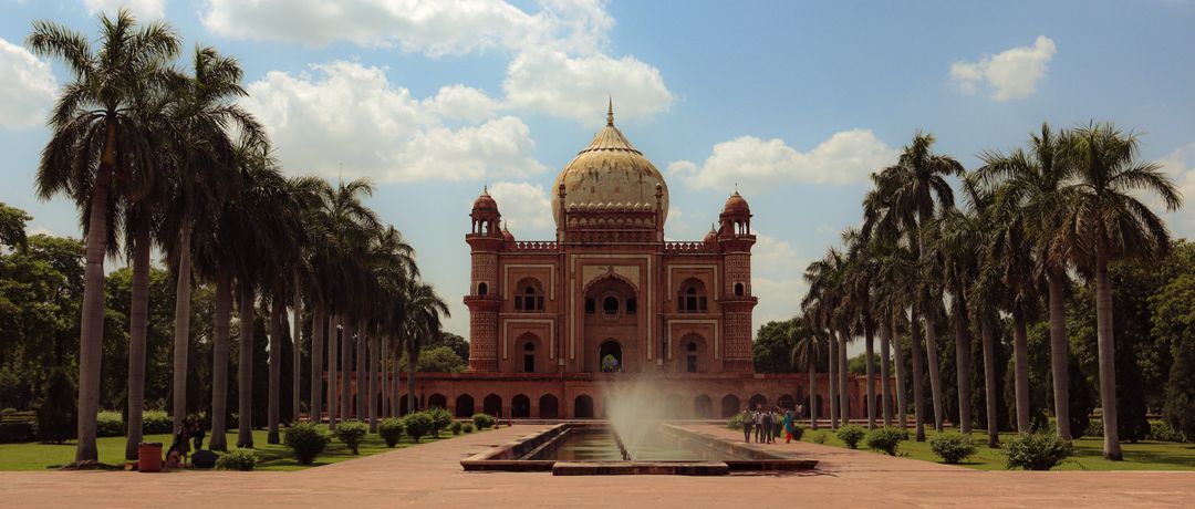 A scenic view of Safdarjung Tomb in New Delhi with palm trees and a fountain under a bright blue sky., travel destination in India, where a local eSIM keeps you connected