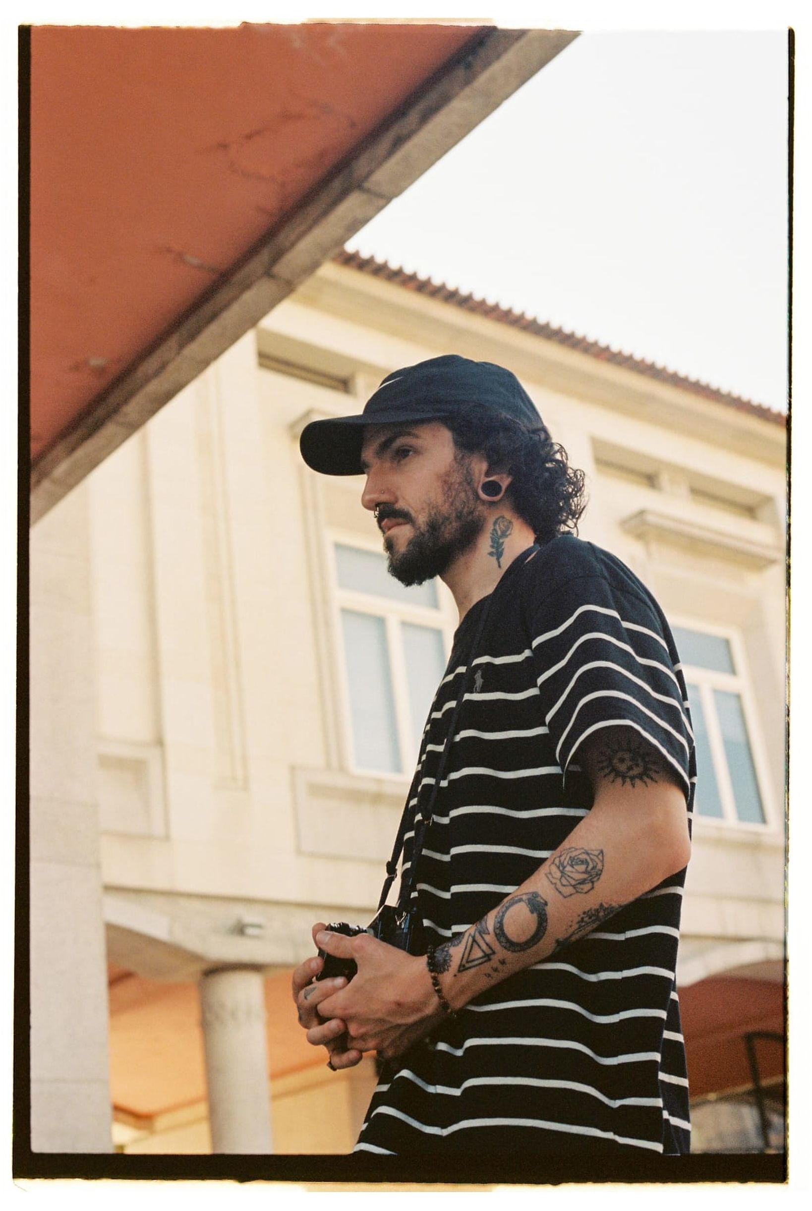 A stylish photographer in a striped shirt capturing moments with a DSLR.
