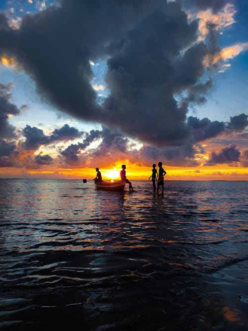Children Standing on Sea Water During Sunset