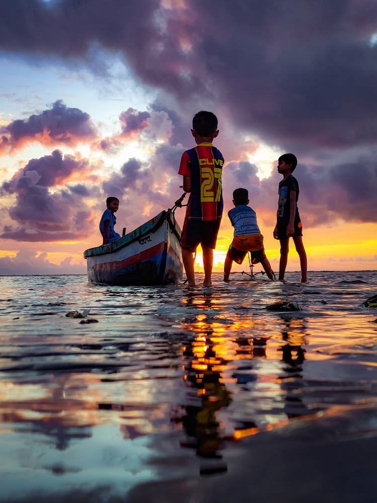 Kids Playing With Boat On Seashore