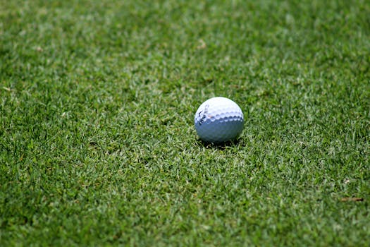Close-up of a golf ball resting on a beautifully maintained green fairway, perfect for a sunny game day.