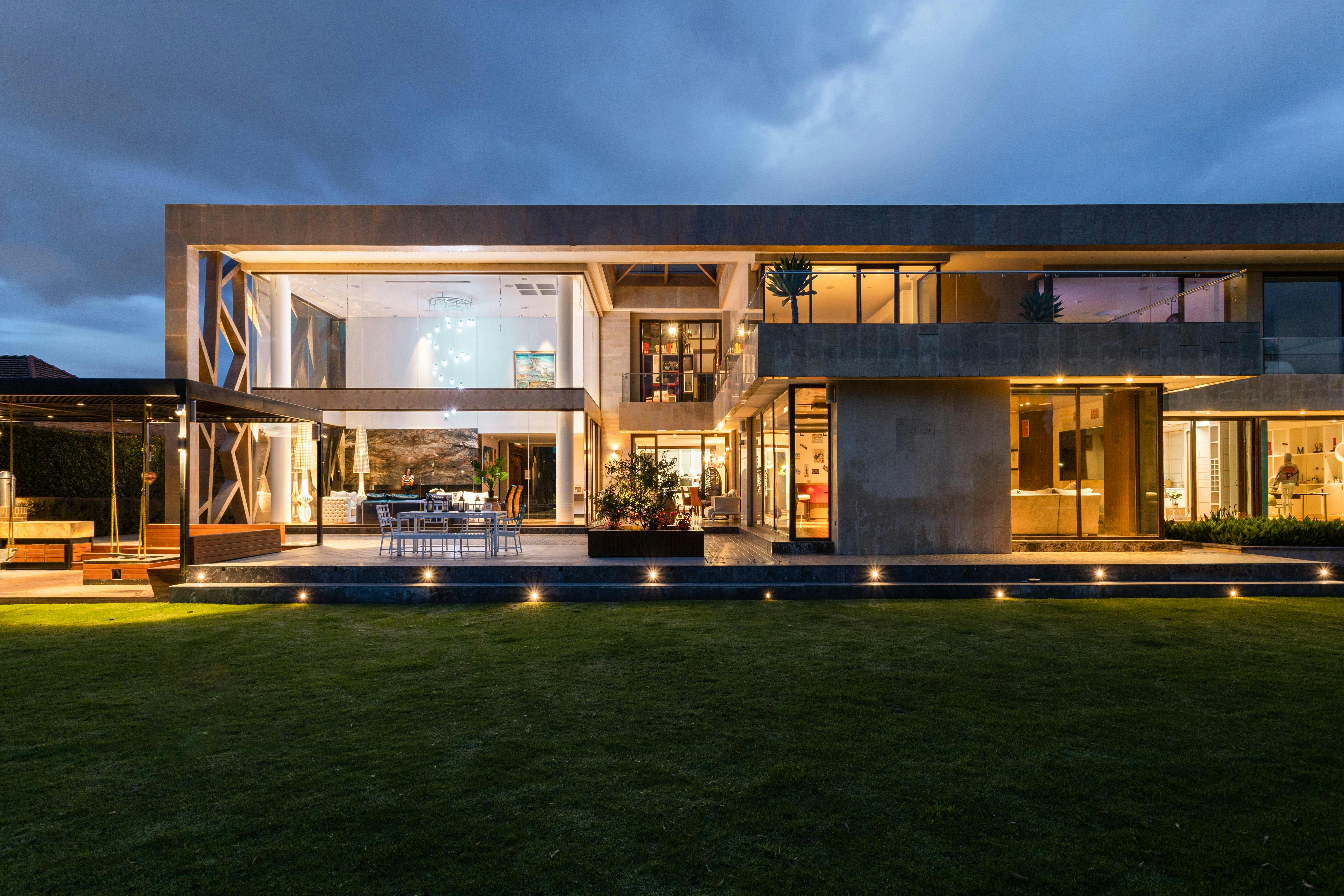 Explore a contemporary villa with a stunning facade, illuminated at dusk, highlighting its modern architecture.
