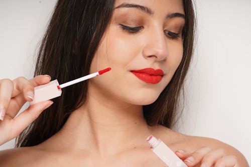 A Topless Woman Holding a Red Lipstick