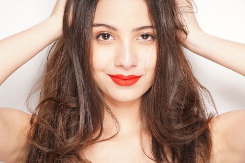 Free Close-up portrait of a smiling woman with brown hair and red lipstick against a white background. Stock Photo