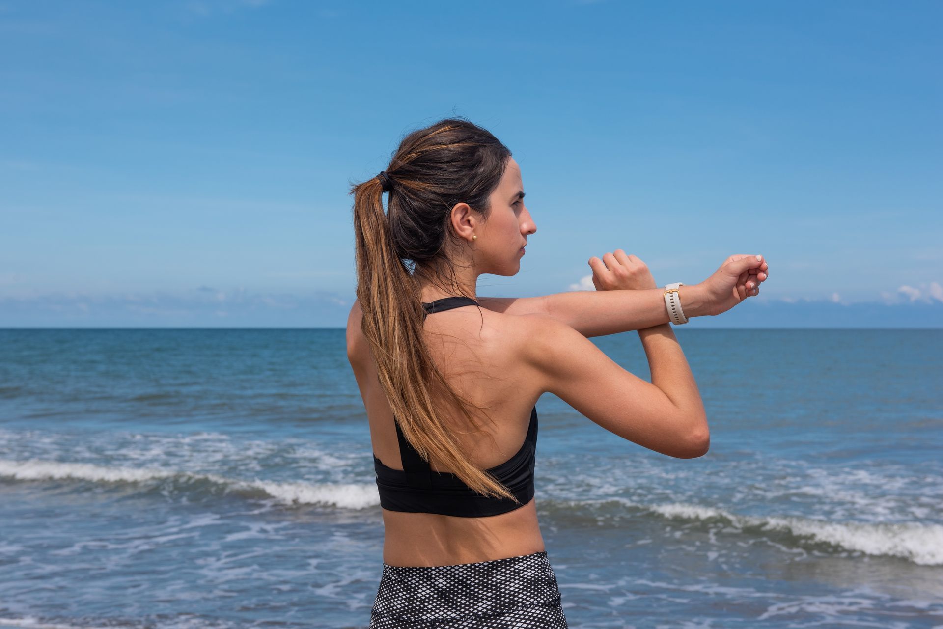 Fit woman stretching on Manzanillo del Mar beach in Colombia with ocean in background