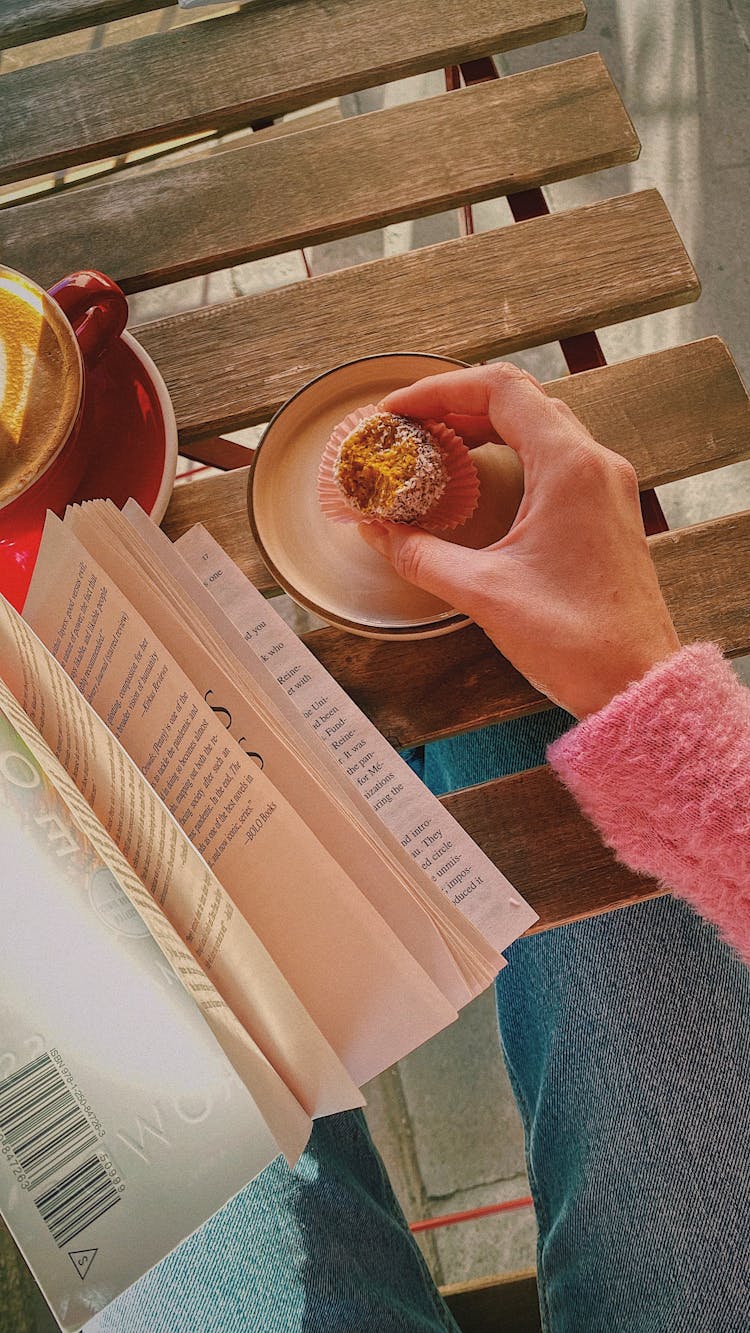 Woman Hand Holding Cupcake And Book