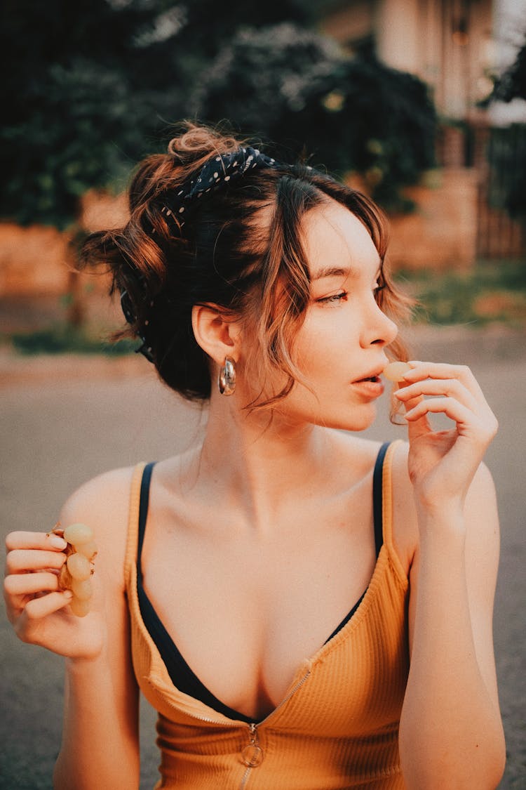 A Woman Eating Green Grapes While Looking Afar