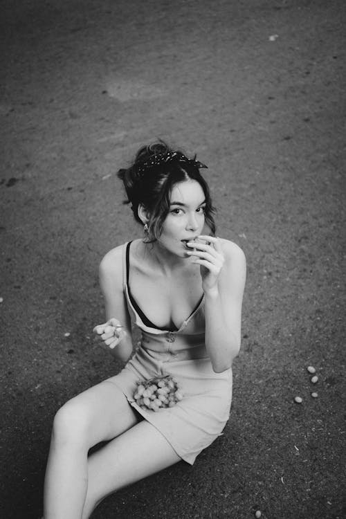 Woman in Spaghetti Strap Dress Sitting on the Ground while Looking at the Camera