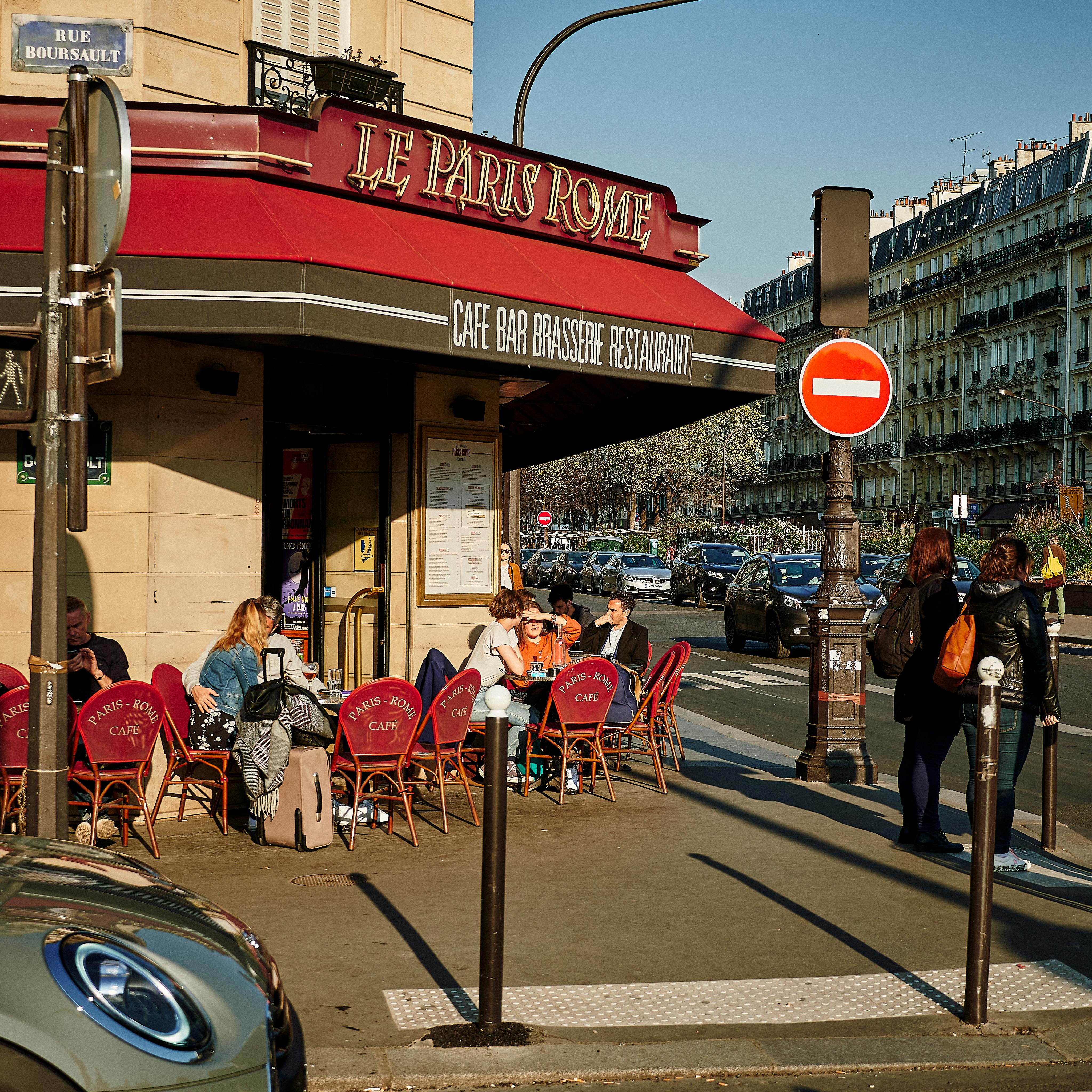 Free A lively Parisian café with people enjoying outdoor seating on a sunny day. Stock Photo
