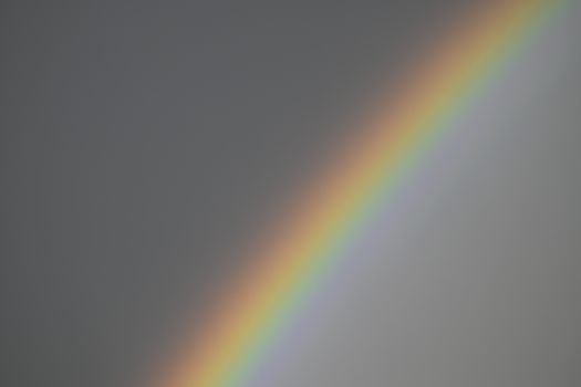 Vibrant rainbow stretching across a cloudy gray sky in Bucharest, Romania.