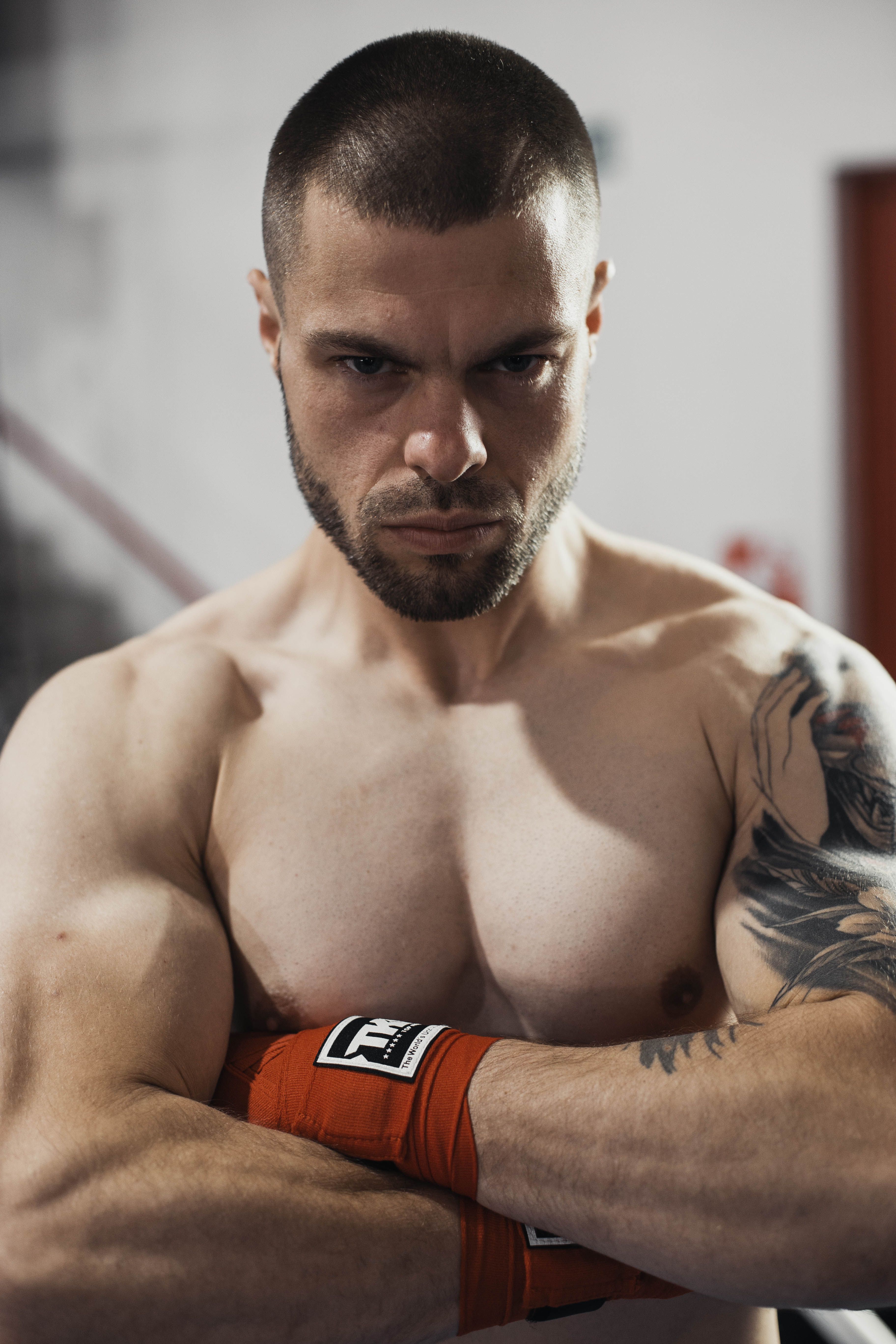 Striking portrait of a tattooed boxer with hand wraps, exuding strength and focus.
