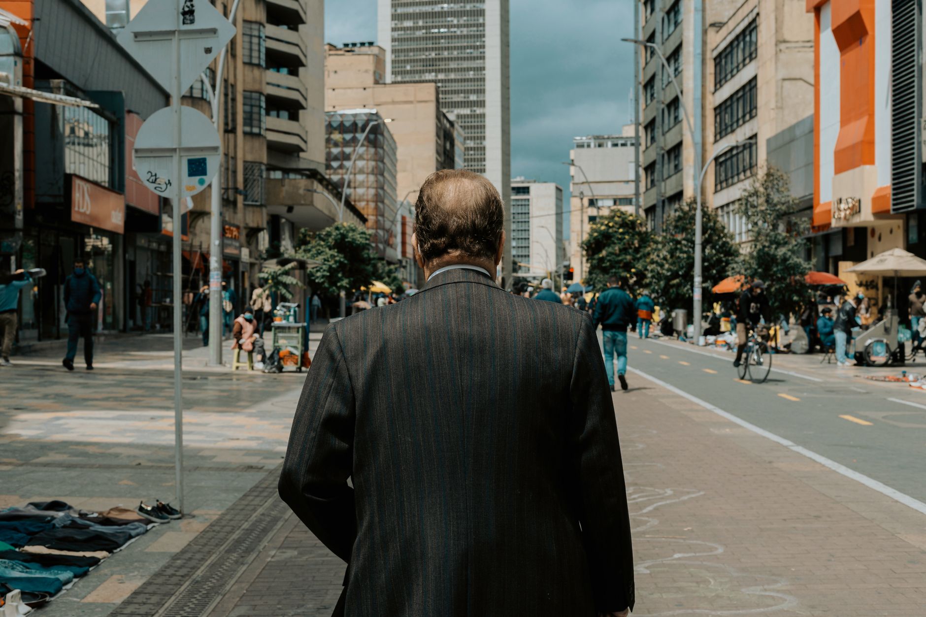 A man in a suit walks along a vibrant street in Bogotá, showcasing urban life.