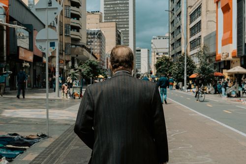 Free A man in a suit walks along a vibrant street in Bogotá, showcasing urban life. Stock Photo
