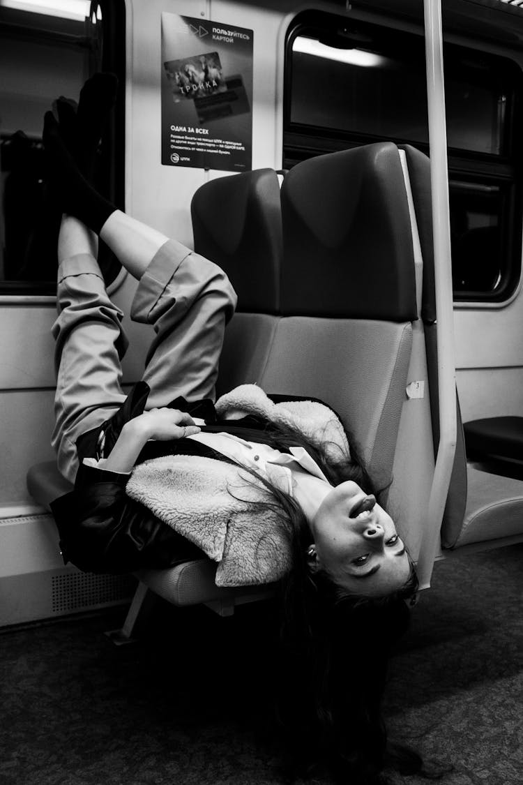 Woman Lying Upside Down On Seats In A Subway 