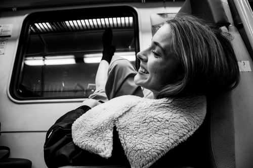 Free Candid black and white photo of a woman smiling and relaxing on a train. Stock Photo