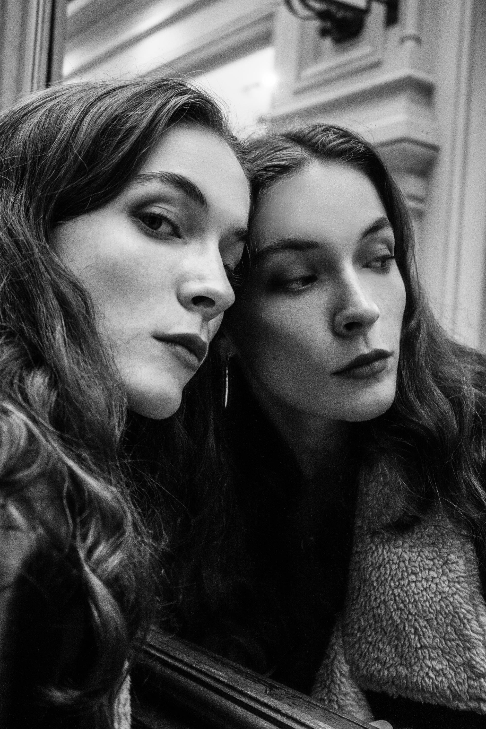 Black and white portrait of a woman in a mirror reflection, capturing elegance and introspection.