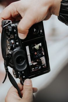 Close-up of hands holding a DSLR camera with viewfinder focused on a subject.
