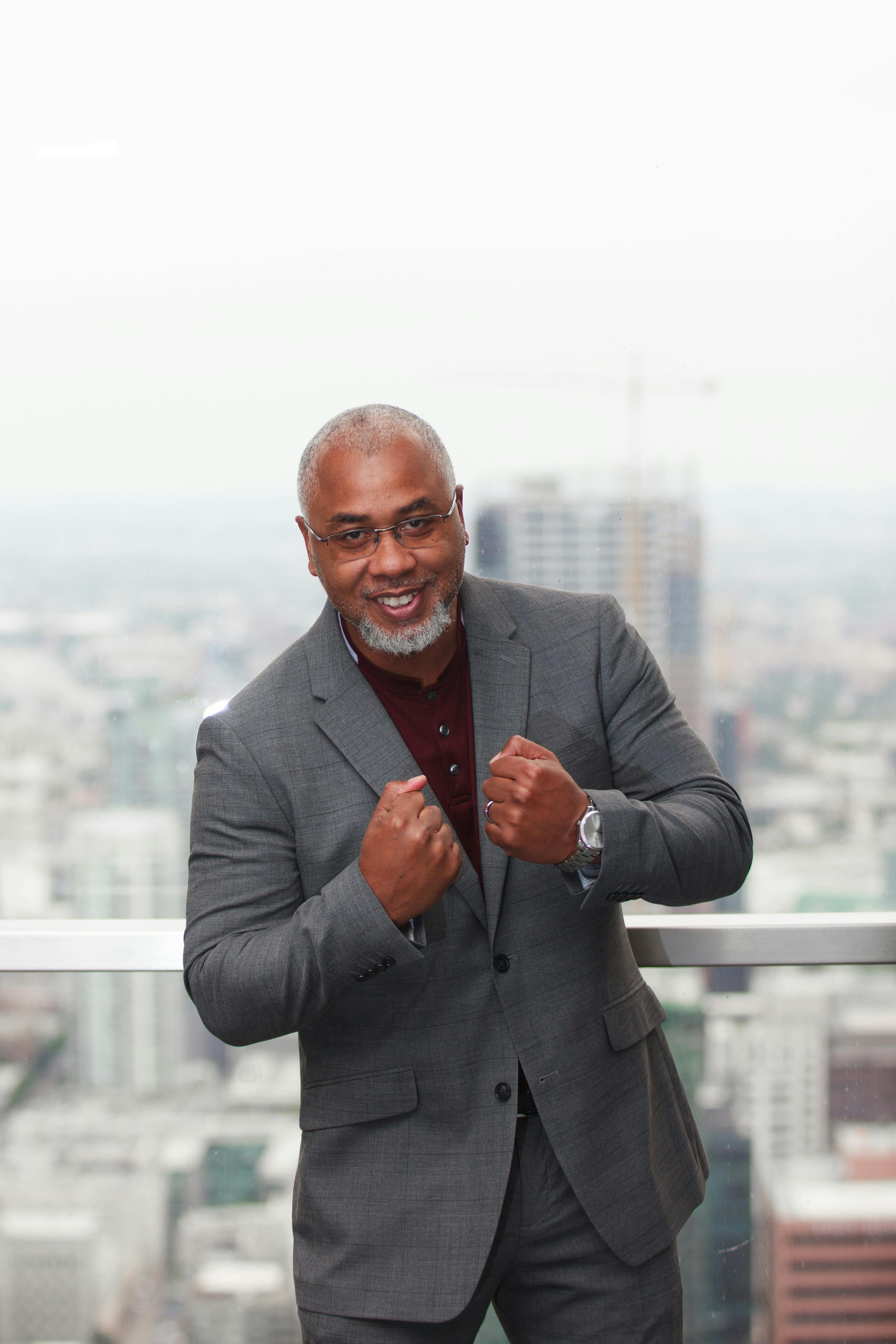 Smiling businessman in a suit poses confidently on a city balcony, showcasing success and optimism.