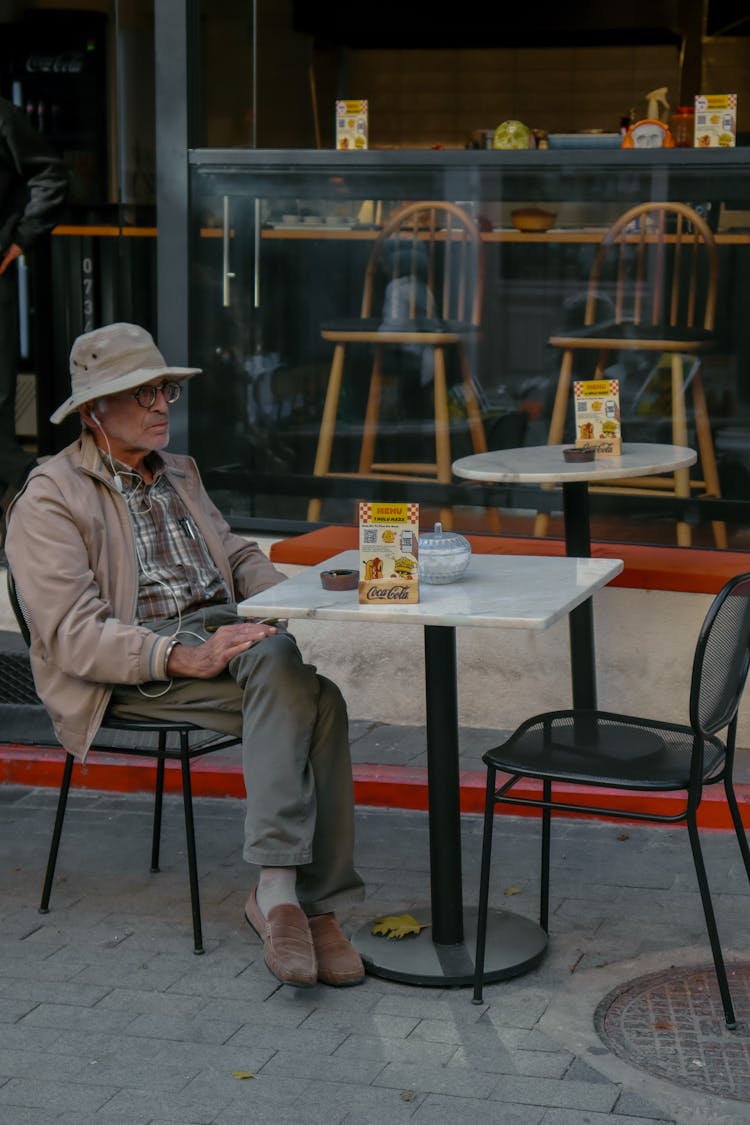 Old Man Sitting At Cafe Table Outdoors