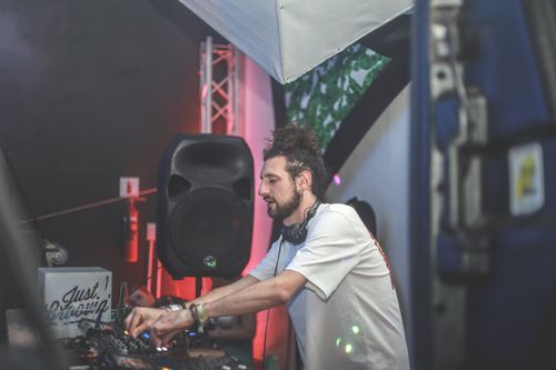 Free A DJ passionately mixing music at an indoor event, surrounded by audio equipment and lights. Stock Photo