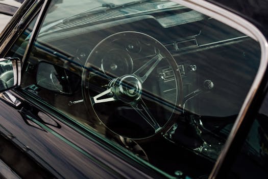 Close-up view of a vintage car interior showcasing the classic steering wheel and dashboard details.
