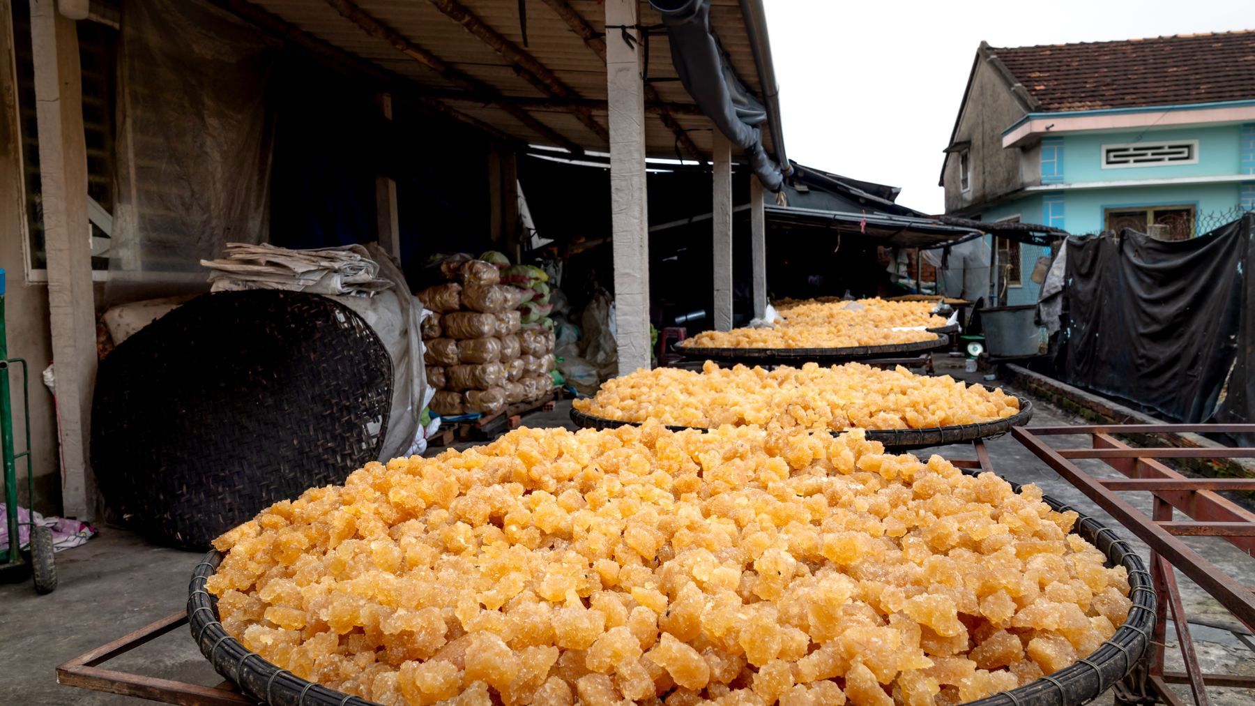 Large baskets of candied fruit drying outside an urban market in Vietnam.