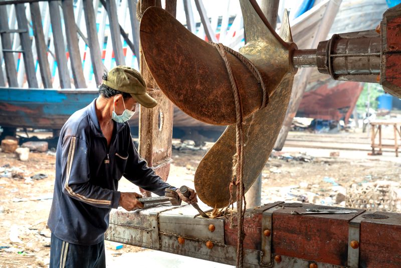 Marine engineer repairing ship machinery in a shipyard
