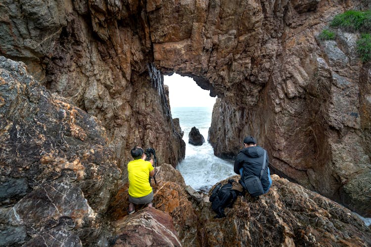 Photographers On A Cave At A Beach