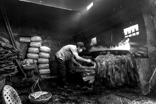 Monochrome image of a man preparing food in a traditional kitchen with a rustic ambiance.