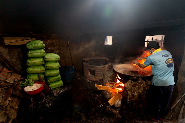 Man Burning A Fire In An Oven In A Dark Barn