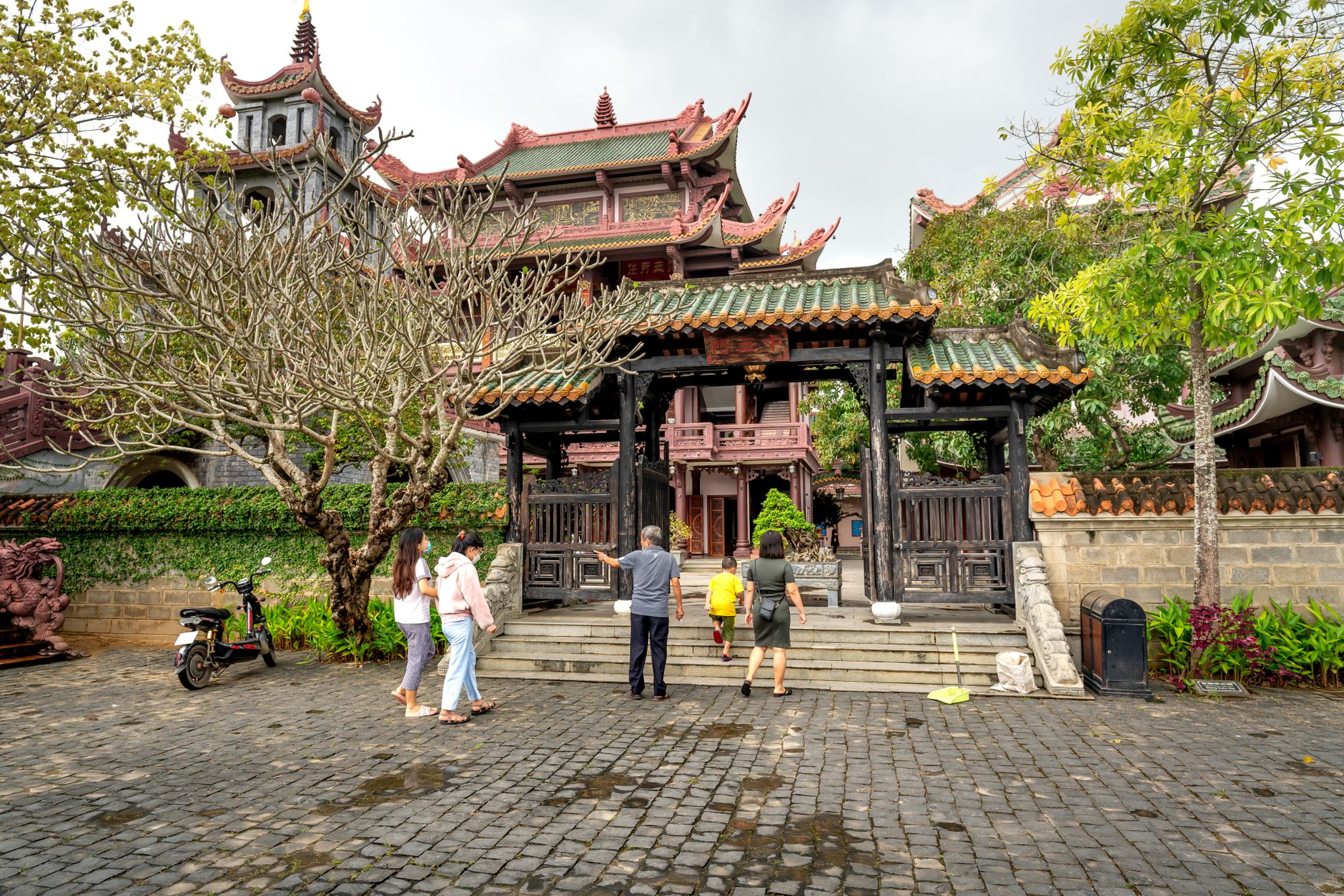 A group of people exploring a traditional Asian temple surrounded by lush greenery in spring.