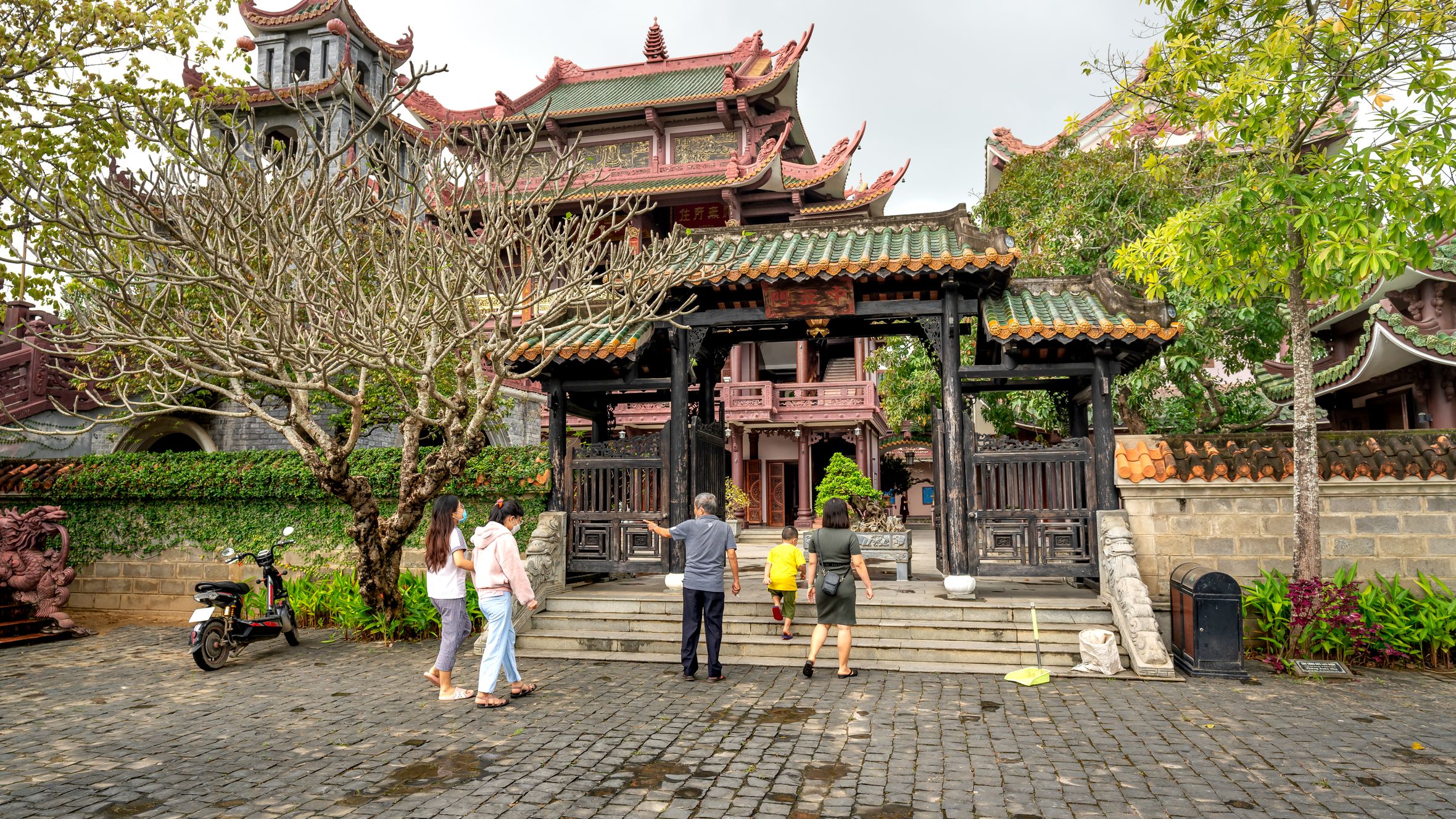 A group of people exploring a traditional Asian temple surrounded by lush greenery in spring.